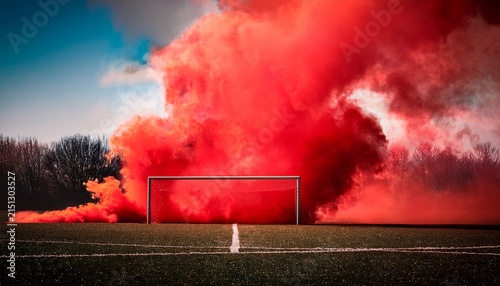 a sports goalpost is enveloped in vibrant red smoke creating a dramatic scene