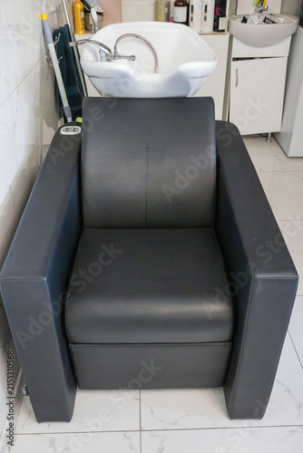 Foto a modern black leather salon chair with an attached white ceramic backwash basin in a bright, clean professional hair studio