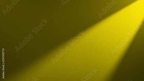 Fotografie Yellow spotlight beam shining diagonally across dark studio background
