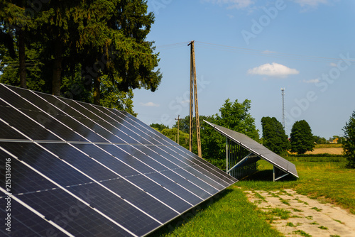 Ground mounted solar panels with wooden power pole against blue sky in countryside