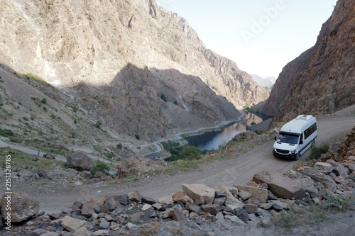 Photography A minibus driving on a dusty road in the Asian mountains
