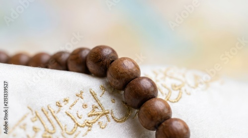 Wooden prayer beads on white fabric with gold calligraphy.