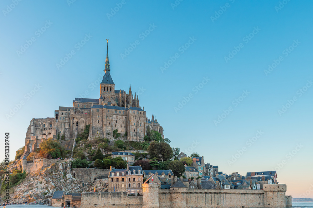 Obraz premium Close up view of Mont Saint-Michel Abbey and fortified village at sunset in Normandy, France. Tidal island with monastery in Normandie. French architecture. Cultural tourism and European landmarks