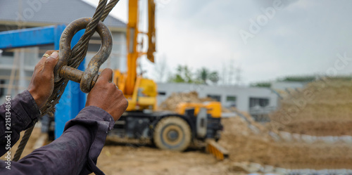 Man hand pulling metal sling of crane to lift cement platform at construction site-banner image.