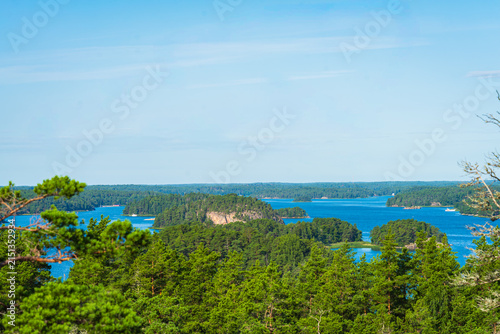 Zoom in aerial view of a single green island surrounded by blue Baltic Sea in Finnish Archipelago