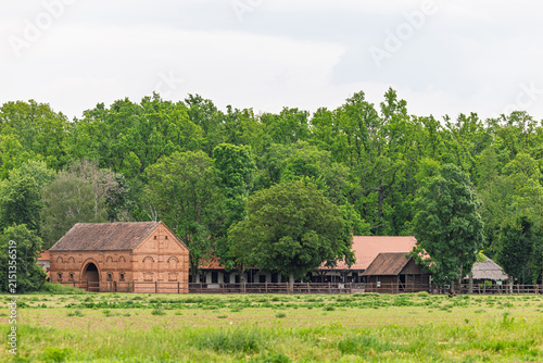 Foto Historic Brick Barn And Farmhouse Amid Lush Green Countryside, Forest And Meadow
