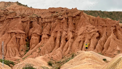 Red badlands rock formations with person in yellow jacket — sense of scale