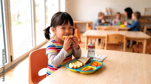 Adorable Japanese Girl Eating Sandwich at a Kindergarten Table with Healthy Snacks