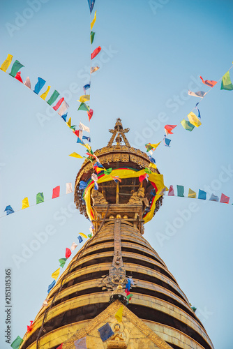 Cuadro en lienzo Vertical view of golden Swayambhunath stupa spire with prayer flags and sky copy