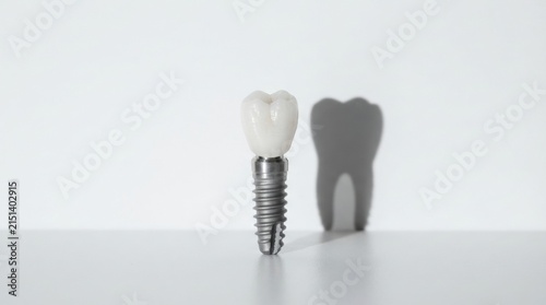 Single dental implant with porcelain crown casting tooth shadow on white background for dental clinic poster and implant service design