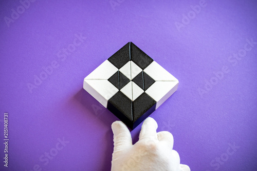 Artificial intelligence core and neural network concept. Hand in white glove presenting a symmetrical geometric puzzle representing AI algorithm structure on purple background.
