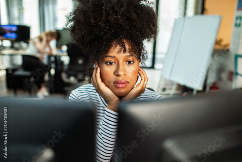 Young woman concentrating at dual monitors in modern office