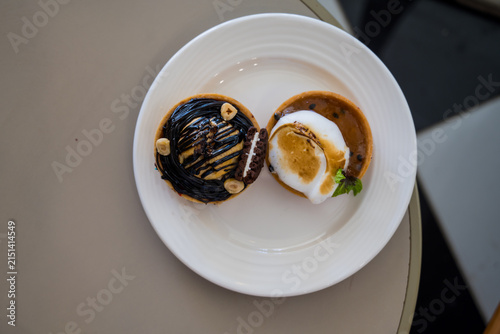 Chocolate and caramel tart desserts on white plate, top view