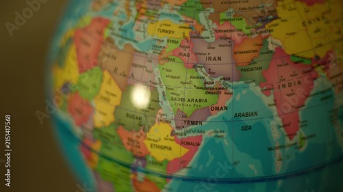 Close-up globe spinning over Middle East and Africa region. Colorful map shows continents with clear country names. Bright spot reflects off globe's glossy surface