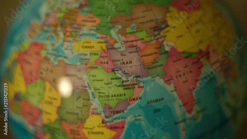 Close-up globe spins, highlighting Middle East countries. Soft light glints off surface, creating gentle reflections. Vibrant colors define continents, making geography visually engaging