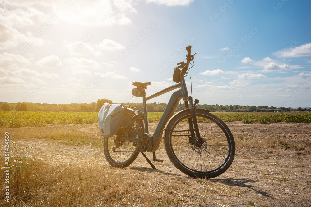 Fototapeta premium Bicycle parked on a dirt path near a field during sunny afternoon hours