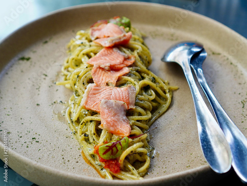 Close-up of gourmet salmon seaweed carbonara pasta served elegantly on a rustic ceramic dish