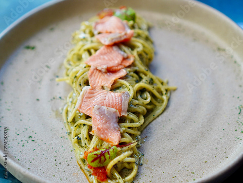 Delicious creamy seaweed carbonara spaghetti topped with tender salmon slices served on a beige ceramic plate