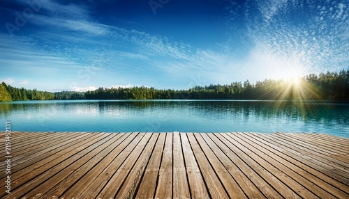 wooden deck at lake under blue sky