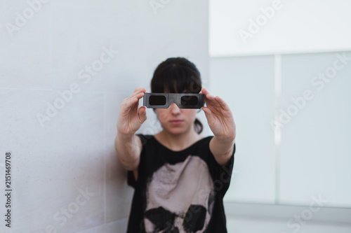 Una mujer sujeta unas gafas negras para ver un eclipse. Protección solar para la observación segura de un eclipse total. Accesorio para observar el eclipse de agosto de 2026 en España