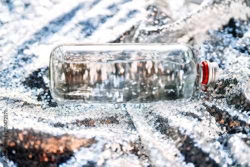 Cuadro en lienzo Clear glass bottle with water on sparkling sequins background