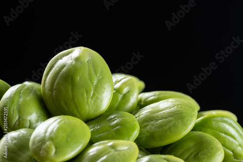 Pile of fresh stink bean seeds on black background.