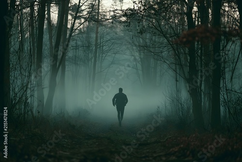 Silhouette of a runner in a misty forest at dawn