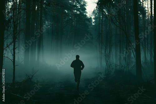 Silhouette of a runner in a misty forest at dawn