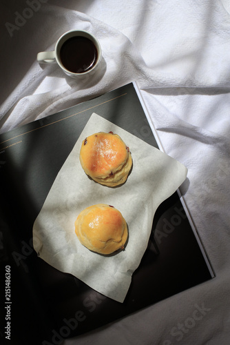 Scones sit invitingly on sheet of white parchment paper bath with morning light, ready for enjoyment.