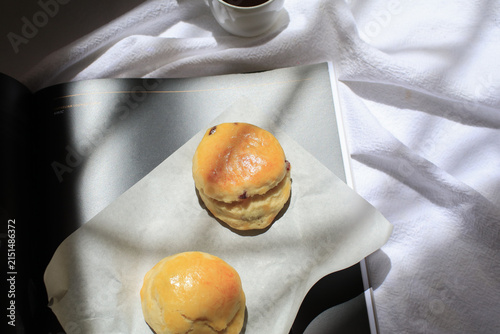 Scones sit invitingly on sheet of white parchment paper bath with morning light, ready for enjoyment.