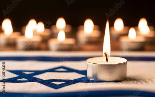 Burning candle and flag of Israel on black table. Holocaust memory day