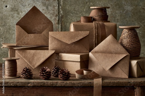 Brown envelopes arranged beside wooden table with stationery and wrapped presents under clean editorial daylight.