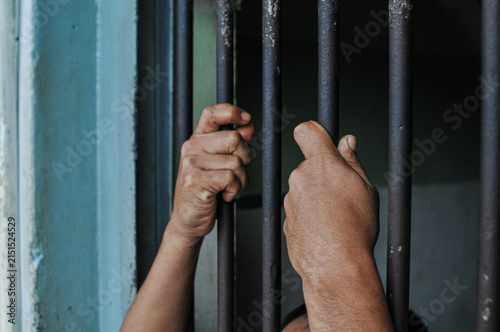 Obraz na plátne Close up of prisoner hands gripping steel prison cell bars representing captivit