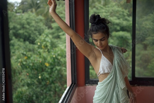 Obraz na plátne Young woman in white crochet bikini top and draped fabric poses gracefully