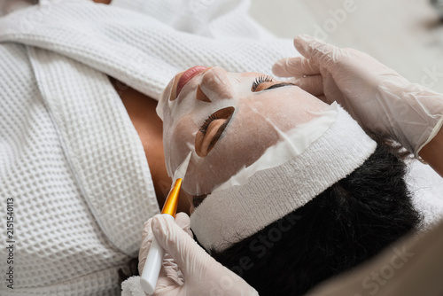 Принти на полотні Woman receiving a hydrating sheet mask facial treatment at a beauty salon for sk