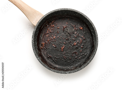 Fotografía Burnt food residue in a dirty non-stick frying pan with a wooden handle, isolate
