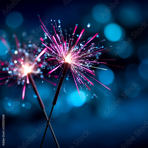 Close up of burning sparklers with bright light flares against blurred night