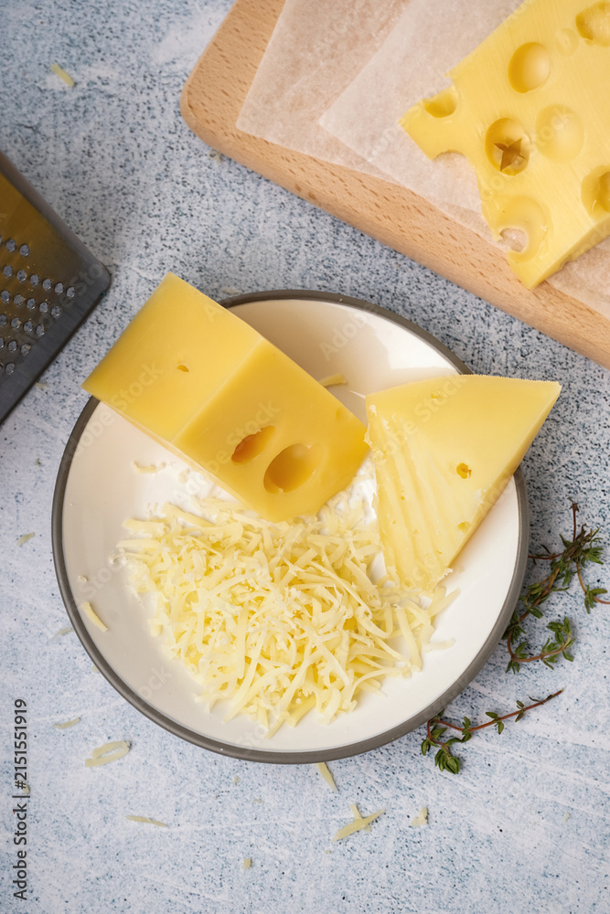 Fototapeta premium Plate and board with pieces of Swiss cheese on white table