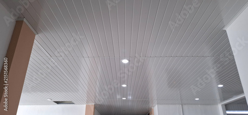 Konstfotografi Low angle perspective shot of a modern white PVC striped ceiling featuring recessed LED downlights and structural side pillars