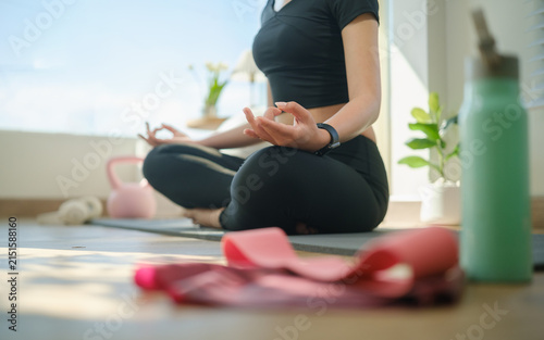 Young Asian woman practicing seated meditation and mindful breathing on an exercise mat at home.