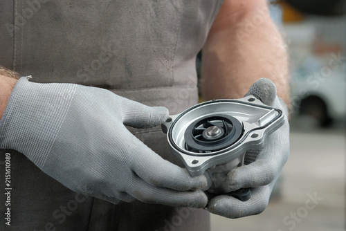 Auto parts.An auto mechanic prepares a water pump for replacement. The car mechanic has a new water pump in his hands.Control over the serviceable condition and integrity of the product.