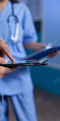 Doctor Using Digital Tablet with Nurse in Blue Scrubs Background