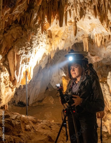 Cave photographer with camera and headlamp gear.