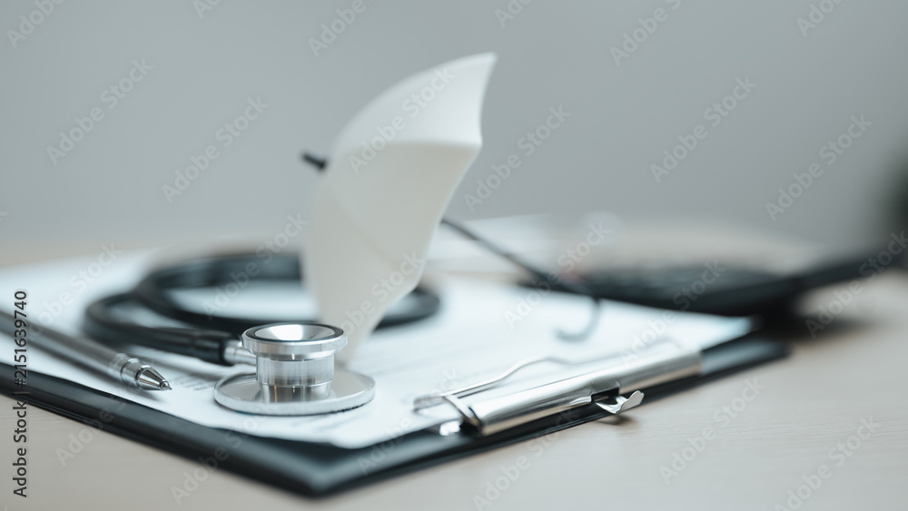 Obraz premium Medical insurance concept with stethoscope, clipboard, and umbrella illustrating healthcare coverage, financial protection, and patient benefits.
