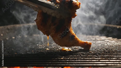 Grilled Chicken Leg Being Lifted With Tongs Releasing Smoke In Vivid Culinary BBQ Scene