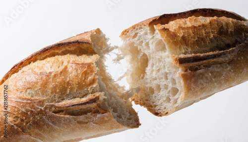 Fresh baguette crusty bread golden brown artisan bakery close up white background French rustic delicious torn