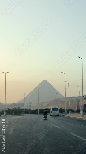 Vertical Shot of Giza Pyramids Rising above Cairo Urban Skyline Seen from City Road at Dusk