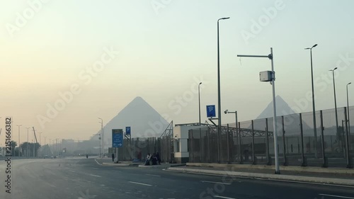 View from driving car of Giza Pyramids Rising above Urban Skyline Seen from El-Haram Street road in Cairo