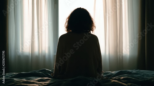 Lonely Woman Sitting Alone on Bed by Window in Dark Bedroom