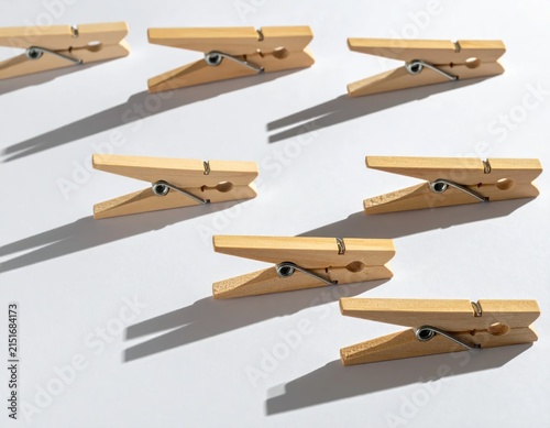 Wooden clothespins on white surface with shadows.